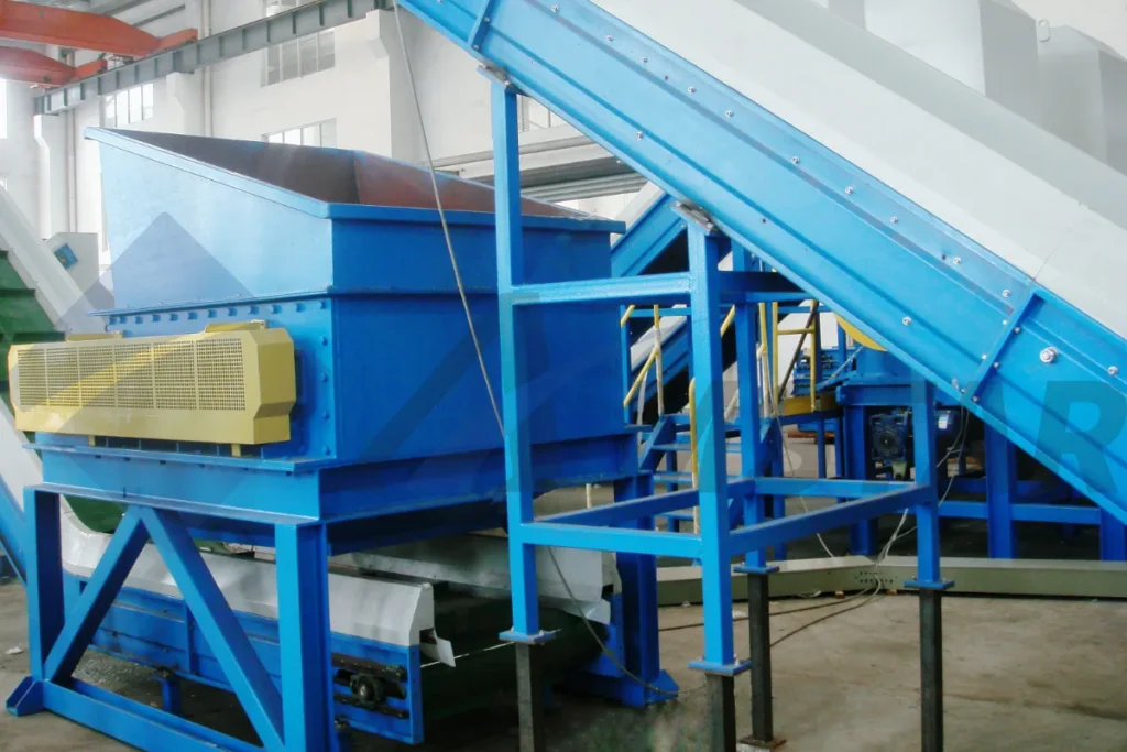 Debaler for PE film bales – blue hopper, yellow drive guard and inclined infeed conveyor