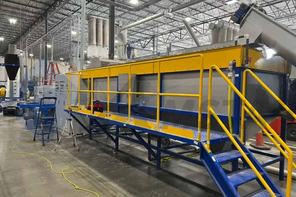 Float sink separation tank in a PE film washing line, with yellow walkway railings