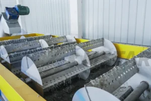 Perforated paddle drums pushing floating PE film flakes along the tank