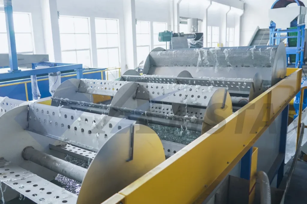 Rotating paddles moving washed film flakes through the float sink tank