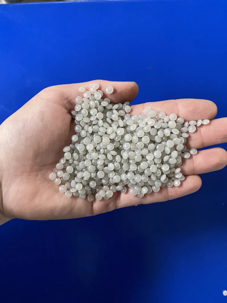 Recycled PE pellets held in a hand